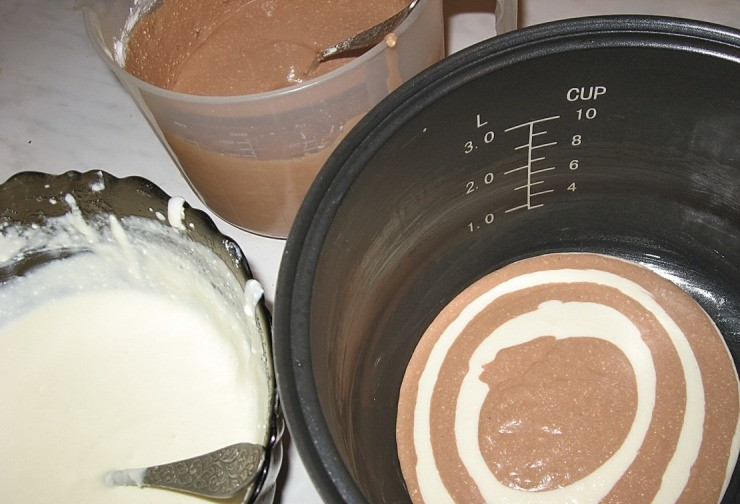 1. Этап. Творожный десерт в мультиварке: Чашу мультиварки смазываем сливочным маслом. А теперь начинаем делать узор: вливаем ложку белой массы, затем томной, опять белой и так далее. В конце делаем красивые разводу на поверхности при помощи зубочистки.