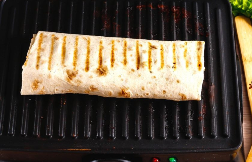 1. Этап. Курица в лаваше: Смажьте их оставшимся майонезом, заверните начинку в лаваш в виде рулета. Прогрейте электрогриль или сковороду-гриль и выложите на нее лаваш. Поджарьте его до румяности примерно 2-3 минуты.