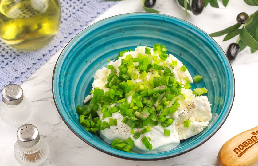 1. Этап. Канапе Яйца змеи: Выложите творог любой жирности вместе со сметаной в глубокую емкость или чашу для блендера. Промойте и измельчите зеленый лук, побеги зеленого горошка и выложите к творогу.