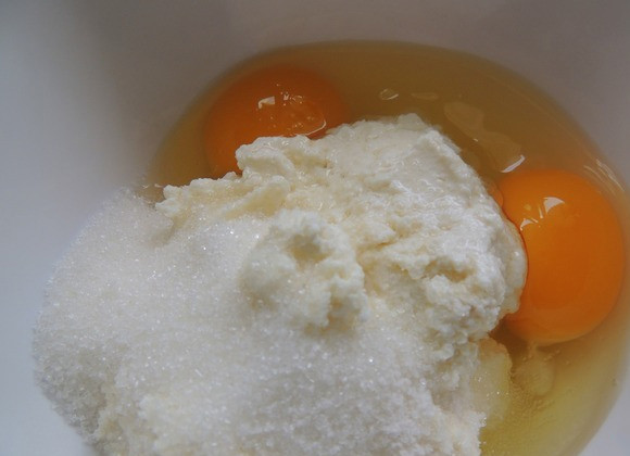 1. Этап. Творожный манник на молоке: Творог соединяем с сахаром, щепоткой соли, яйцами, ванилином и разрыхлителем. Взбиваем массу. Манку высыпаем в отдельную посуду, заливаем молоком.