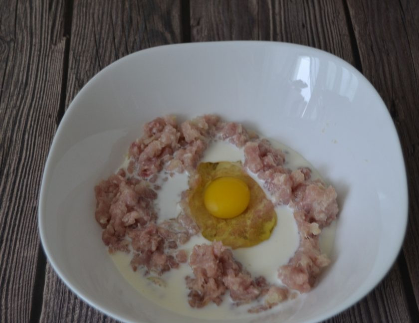 1. Этап. Куриные котлеты с мукой: Фарш заправьте луком, влейте в него молоко и вбейте 1 куриное яйцо.