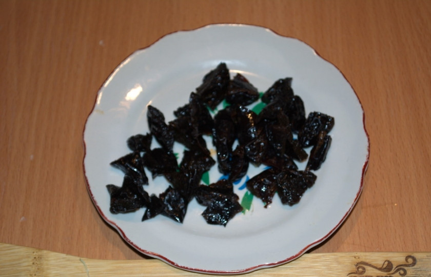 1. Этап. Мясо по-староуральски: Чернослив промойте и нарежьте кусочками. Добавьте к капусте.