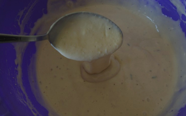 1. Этап. Оладьи с луком и яйцом на кефире: Два куриных яйца поставьте вариться на 8 минут. Тем временем приготовьте тесто. Смешайте сырое яйцо, кефир и добавьте соль. Всё хорошо перемешайте, а затем постепенно введите муку, погасите соду уксусом. Тесто должно получиться по консистенции как сметана.