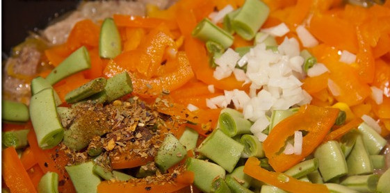 1. Этап. Жареный лагман: 4. Настало время добавлять все остальные овощи, кроме помидор - чеснок мелко режем, перец - произвольно, а фасоль нарезаем кусочками в сантиметр. Также добавим выбранные специи. Бросаем к мясу, и держим под крышкой.