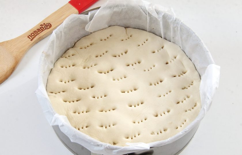 1. Этап. Пирог с колбасками и карамелизированным луком: Слоеное тесто раскатайте чуть больше, чем размер формы. Вырежьте круг и накройте тестом колбаски, подгибая края внутрь. Сделайте проколы вилкой для выхода пара.