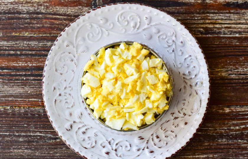 1. Этап. Оливье с ананасом: На него выложите вареные куриные яйца, которые тоже нарежьте кубиками.