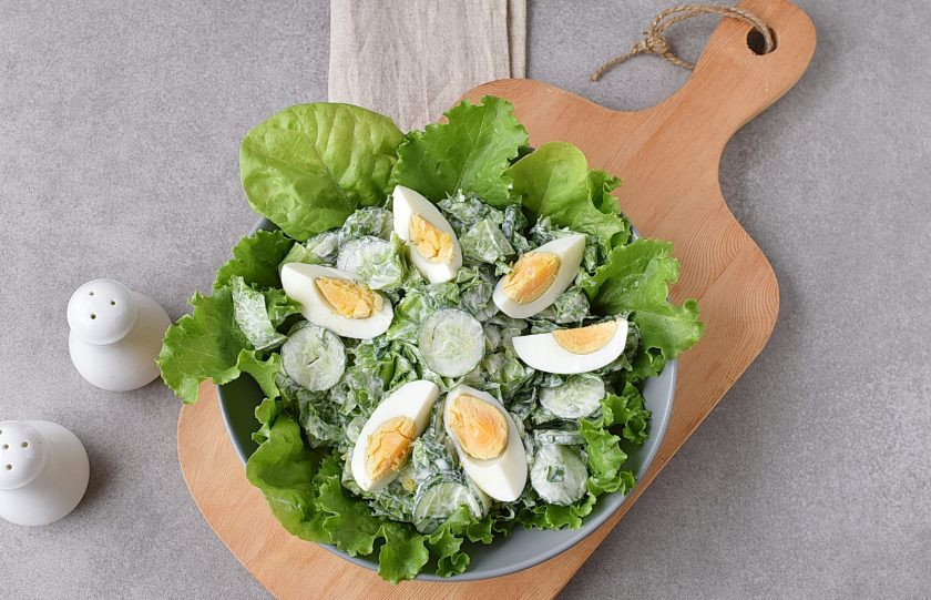 1. Этап. Салат со сметаной: Выложите заправленный салат на салатные листья, украсьте дольками яйца.