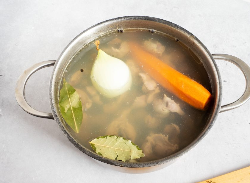 1. Этап. Заливное из куриных желудков: В кипящий бульон добавьте морковь, лук, чеснок, лавровый лист и горошки перца. Посолите по вкусу и варите ещё полчаса.