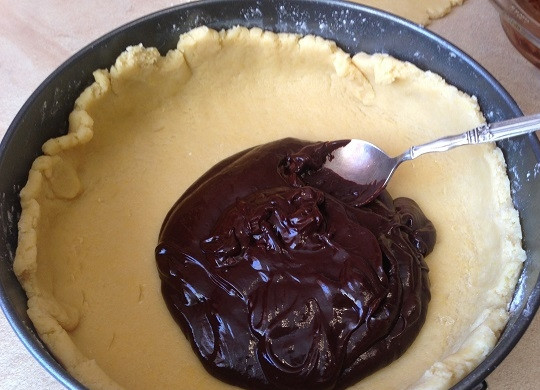 1. Этап. Песочный пирог с шоколадным кремом: 8. Делим тесто на две части. Одна — 2/3, вторая, соответственно, 1/3. Раскатываем большую часть теста в круг диаметром на 2 см больше, чем диаметр формы. И выкладываем в форму. Распределяем, формируя бортики. Выкладываем остывший шоколадный крем, разравниваем его.