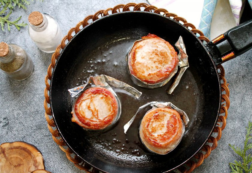 1. Этап. Свиные медальоны в беконе запеченные с овощами: В сковороде разогрейте растительное масло и разогрейте на сильном огне. Обжаривайте медальоны с двух сторон до золотистой корочки.