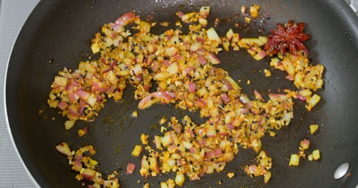 1. Этап. Вкусная цветная капуста во фритюре: 5. Очистите чеснок и измельчите его, имбирь натрите на мелкой терке. Очистите и нарежьте меленько лук. Разогрейте сковороду с 1-2 столовыми ложками масла, выложите чеснок, имбирь, оставшуюся ложку гарам масала, кориандр молотый, анис, затем добавьте лук. Обжаривайте несколько минут.