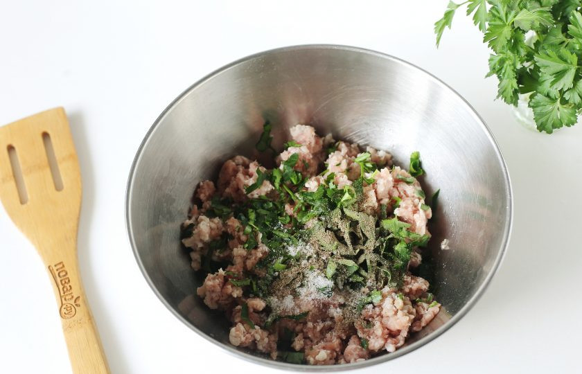 1. Этап. Мясные сочни с грибами: Фарш переложите в глубокую миску. Влейте 50 мл. холодной воды, добавьте рубленую зелень, соль и специи по вкусу. Хорошо все перемешайте.