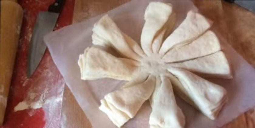 1. Этап. Булочки, политые шоколадом: Приготовьте второй пирог: основа у него аналогичная – четыре тонких пласта, пересыпанных сахаром и разрезанных на 16 частей. Возьмите одну полоску и положите на вторую. Повторите со всеми полосками.