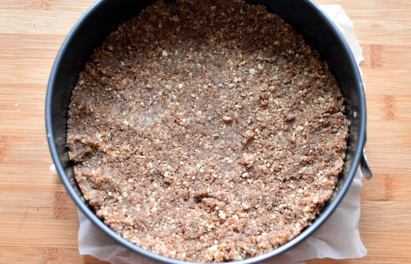 1. Этап. Тыквенный чизкейк без выпечки: Добавьте молотые обжаренные орехи и растопленное сливочное масло. Хорошо перемешайте и выложите в разъемную форму ровным слоем. Хорошо утрамбуйте. Дно формы застелите бумагой для выпечки – просто положите бумагу и защелкните ее бортиком. Так вам будет проще переложить готовый чизкейк на блюдо.