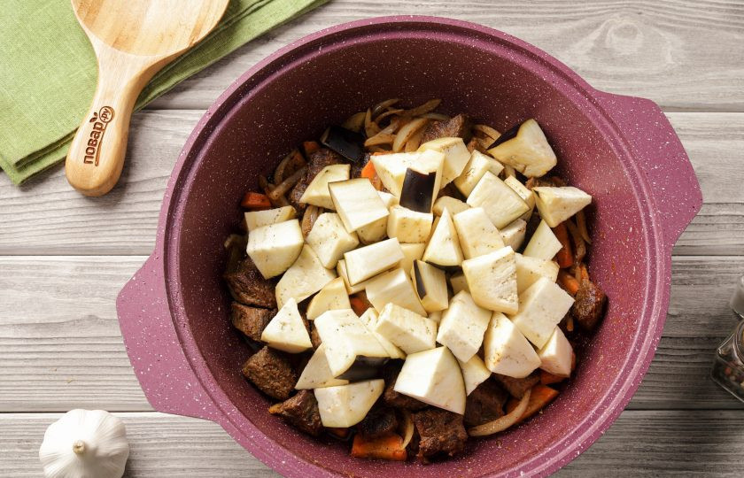 1. Этап. Тушёная картошка с мясом и баклажанами: Баклажан промойте, обсушите и нарежьте крупными кубиками. Добавьте к мясу с овощами.