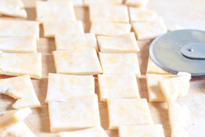 1. Этап. Домашние сырные крекеры: 2. Разделите тесто на части, каждую раскатайте в пласт около 0,5 см в толщину и острым ножом разрежьте на маленькие квадратики.