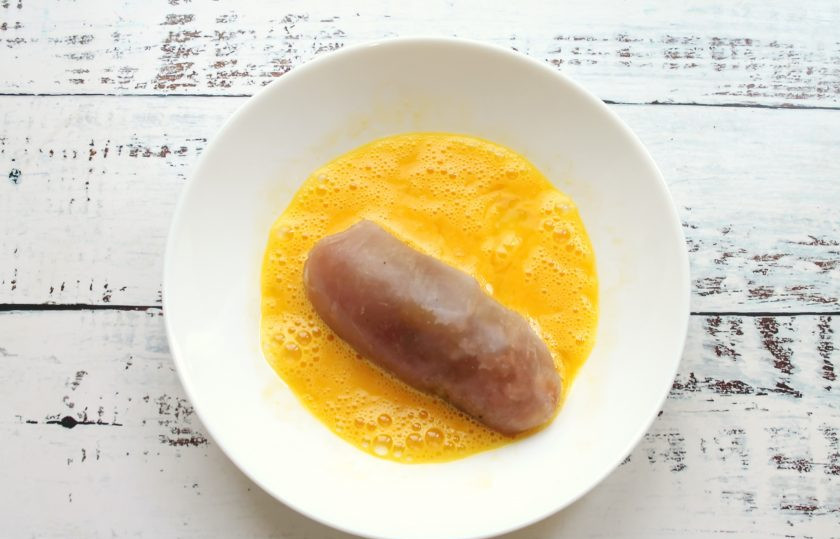 1. Этап. Куриные рулетики замороженные: Яйцо разбейте в миску и перемешайте вилкой. Выложите рулетики в яичную массу и полностью покройте их.