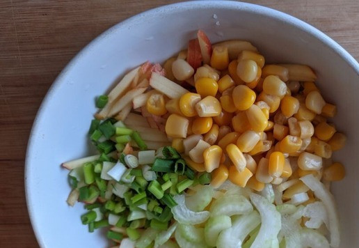 1. Этап. Салат из тунца с йогуртовой заправкой: Добавляем к яблоку кукурузу, зелёный лук, порезанный колечками, сельдерей, порезанный полосками.