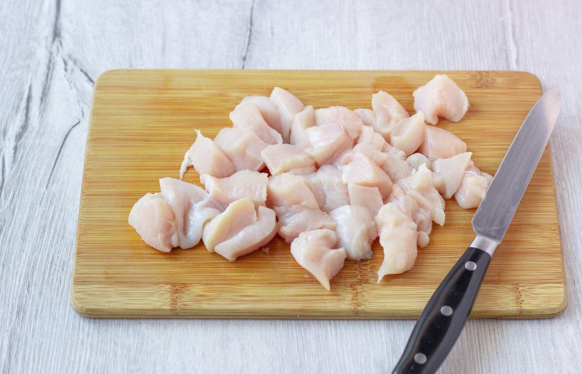 1. Этап. Салат с огурцами и фасолью: Куриное филе помойте, немного обсушите бумажным полотенцем и порежьте на небольшие кусочки.