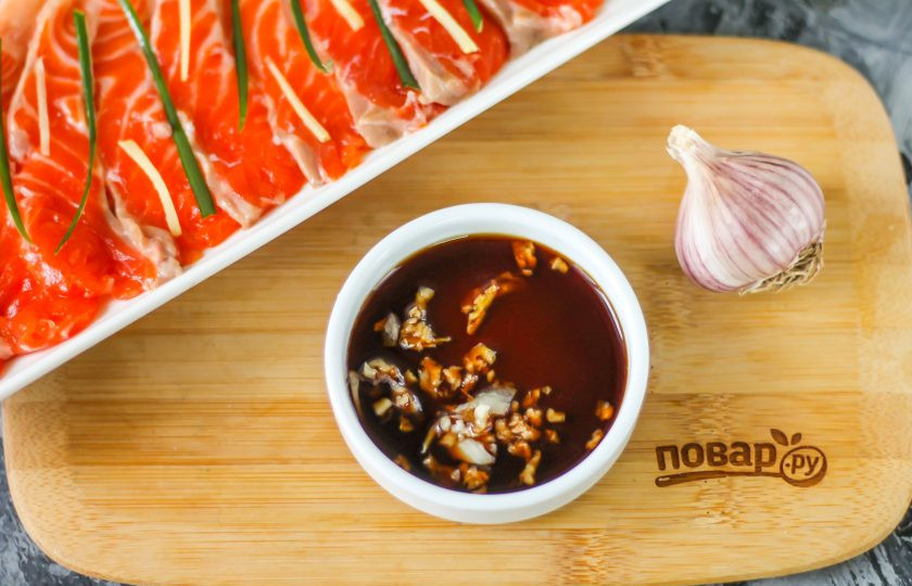 1. Этап. Сашими из лосося: Спрессуйте очищенный зубчик чеснока в пиалу или креманку, влейте туда же лимонный сок и соевый соус, перемешайте.