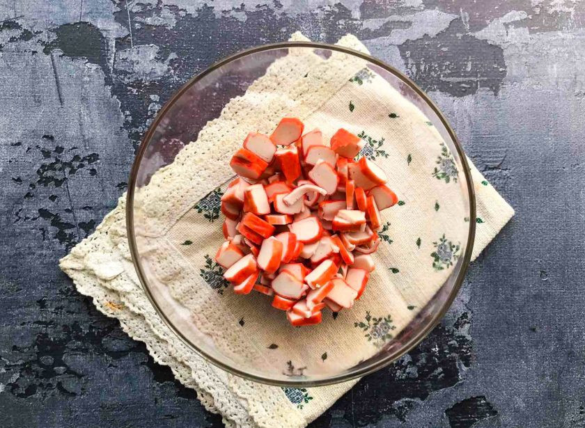 1. Этап. Салат Красное море с креветками и крабовыми палочками: В глубокую тарелку выложите нарезанные крабовые палочки.