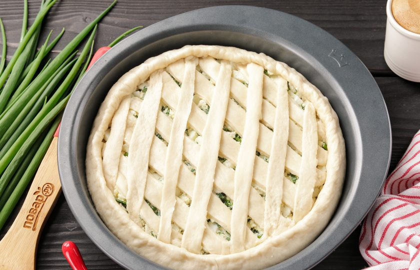 1. Этап. Дрожжевой пирог с яйцом в духовке: Оставшийся пласт теста раскатайте тонко в форме прямоугольника, нарежьте полосками и с помощью их украсьте пирог. Края пирога немного подогните к центру.