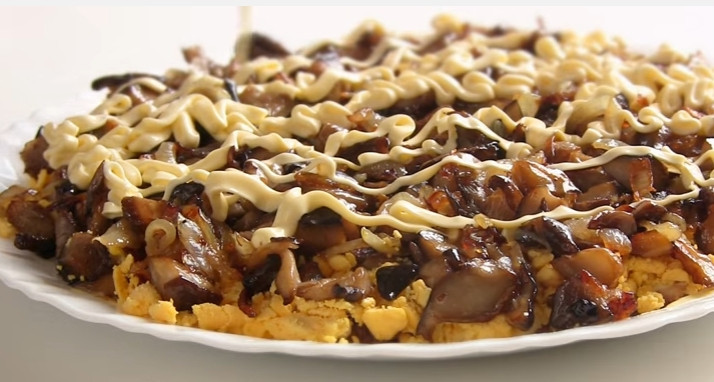 1. Этап. Простой слоеный салат Сказка: 4. Третьим слоем выложите жареные грибы и сделайте сеточку из майонеза.