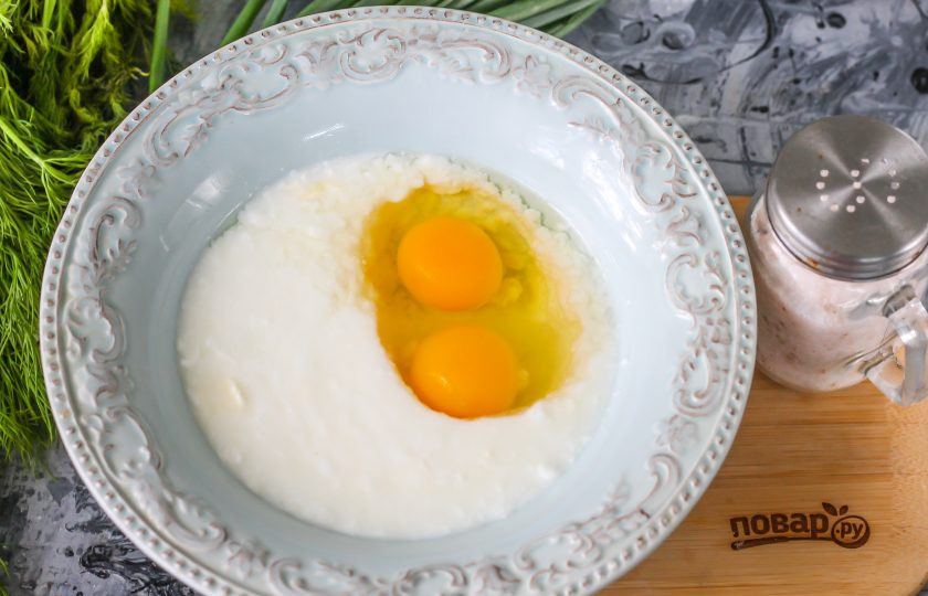 1. Этап. Ленивые оладьи: Влейте кефир любой жирности в глубокую емкость, вбейте туда же куриные яйца и посолите. Тщательно взбейте.