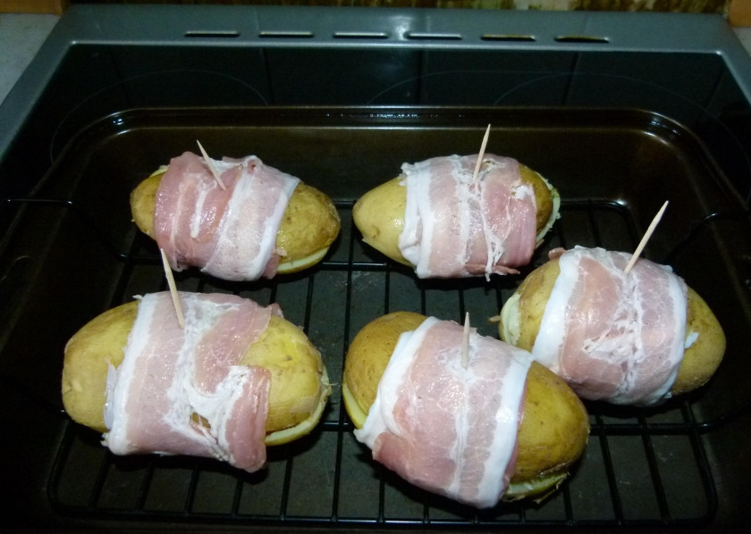 1. Этап. Ароматный запеченный фаршированный картофель: 13. Бекон разделяю на полосы, складываю обе половинки картофеля друг к дружке (сердцевинками внутрь) и заворачиваю вокруг каждой пары полоску бекона, закрепляю зубочисткой.