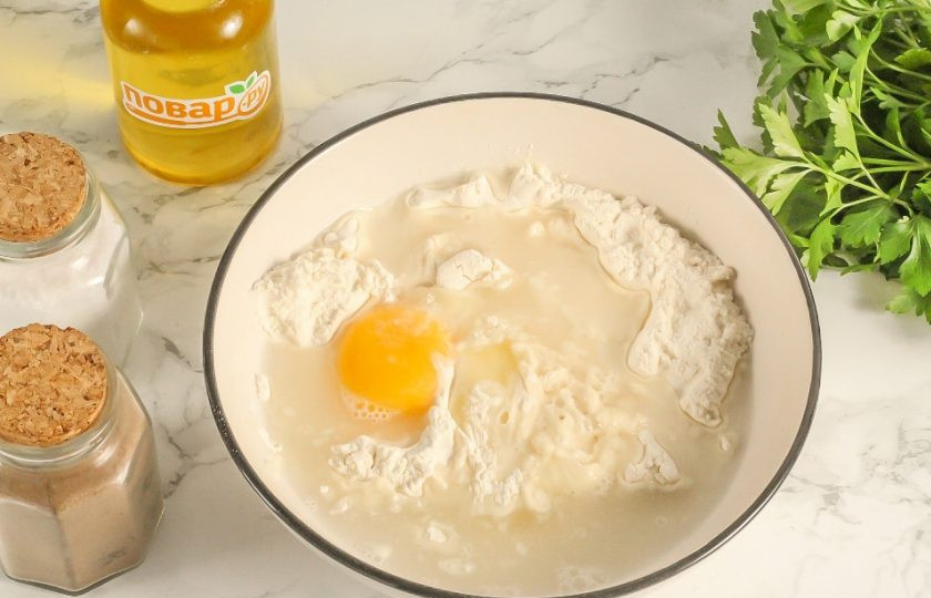 1. Этап. Пельмени Бульмени: В это время замесите тесто для пельменей. Всыпьте 1 стакан пшеничной муки высшего сорта в глубокую емкость: салатник или миску. Вбейте туда же куриное яйцо и влейте холодную воду. Всыпьте соль и все перемешайте.