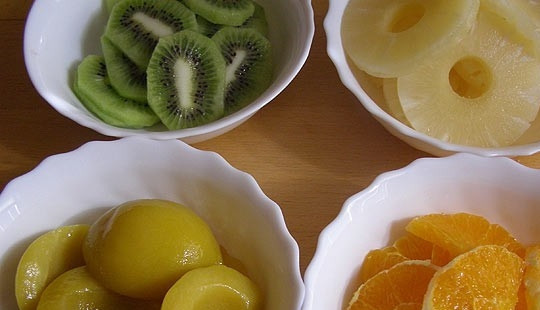 1. Этап. Творожный торт с желе и фруктами: Подготавливаем фрукты для торта. Очищаем апельсин и киви, нарезаем их на дольки. Консервированные фрукты выкладываем на дуршлаг, чтобы слить с них сок. Затем их тоже нарезаем дольками. Небольшую часть нарезанных фруктов отложите на отдельную тарелку - ими мы будем украшать верх торта.