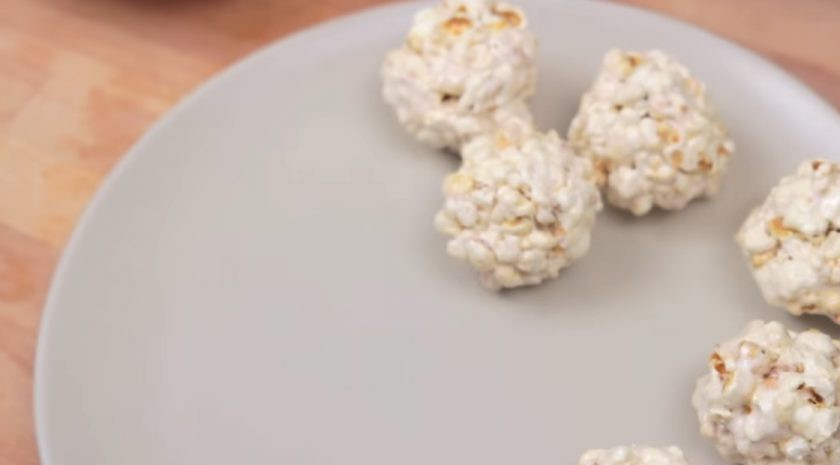 1. Этап. Шарики из попкорна с маршмеллоу: 4. С помощью силиконовой лопатки перемешивайте массу и добавляйте столько попкорна, сколько масса сможет в себя вобрать. Смочите руки растительным маслом и сформируйте шарики.