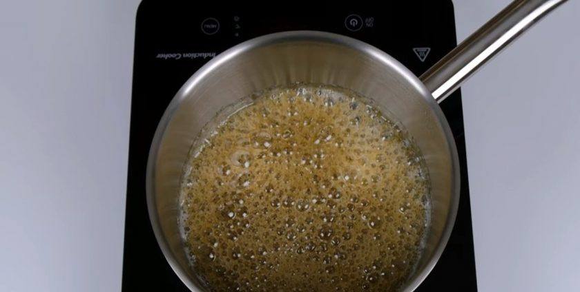 1. Этап. Торт Сникерс с соленой карамелью: 6. Не размешивая, проварите смесь до красивого карамельного цвета. Аккуратно добавьте подогретые сливки, перемешайте, добавьте мягкое сливочное масло и соль. Снимите с огня и остудите. Несколько ложек карамели отложите для украшения.