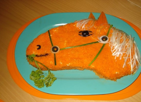 1. Этап. Салат Золотая лошадь: Морковь натрите на мелкой тёрке. Можете использовать варёную морковь, можете сырую. Свежей зеленью сделайте лошадке сбрую. Ушки у лошади морковные. Можете подавать.