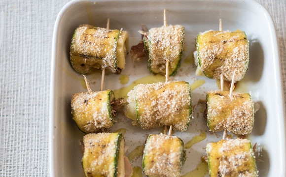 1. Этап. Закусочные рулетики из цуккини: 3. Заверните рулетики, скрепив каждый деревянной зубочисткой, выложите в форму для запекания, поперчите и сбрызните оливковым маслом.