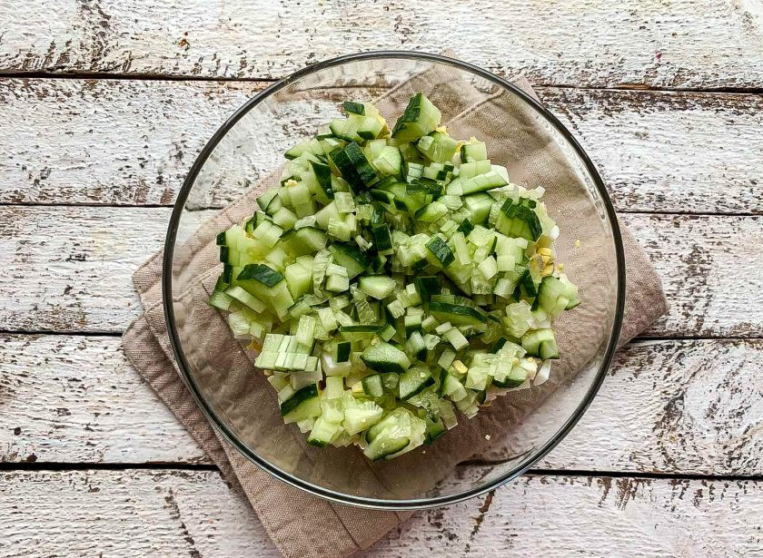 1. Этап. Салат с курицей и огурцами: Огурец помойте под проточной водой, нарежьте и добавьте к остальным ингредиентам.