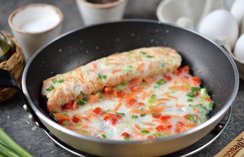 1. Этап. Корейский омлет: Когда низ омлета хорошо схватится, а верх еще будет немного жидковат, начните сворачивать его рулетом. Подливайте белок с овощами как показано на фото.