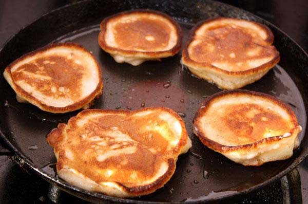 1. Stage. Fritters with apples: In the meantime, heat the pan well, heat the vegetable oil and start frying the fritters with apples . We spread the dough into the pan with a spoon, filling out the pancakes of the desired shape. Put apples on top and dough again. Fry until browned on both sides.