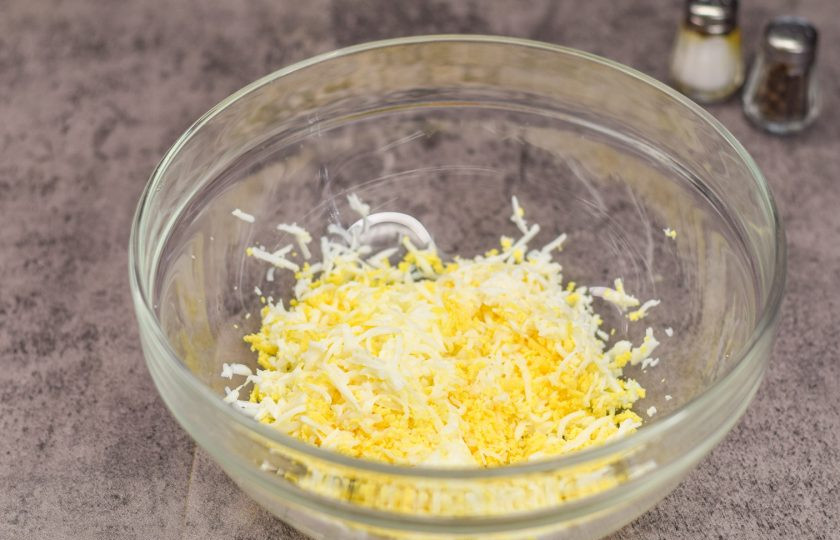 1. Этап. Бутерброды с консервированным тунцом: Куриные яйца отварите вкрутую и остудите, после очистите и натрите яйца на мелкой терке.