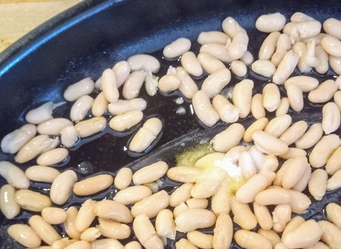 1. Этап. Салат из моркови, апельсина, кунжута, фасоли: Во вторую ёмкость для запекания добавить процеженную белую фасоль, 3 столовых ложки оливкового масла и одну чайную ложку соли. Запекать в течение 30 минут, время от времени перемешивая.