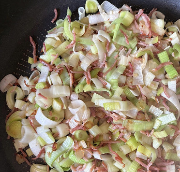 1. Этап. Айнтопф с гречкой и луком-пореем: Порей нарезать полукольцами, добавить к луку с беконом и жарить около пяти минут.
