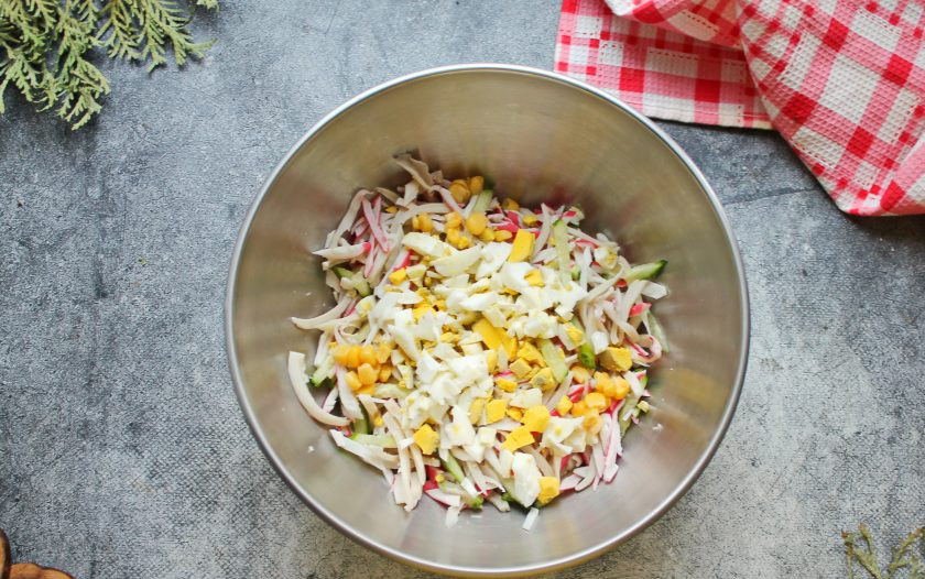 1. Этап. Салат с кальмарами, крабовыми палочками и кукурузой: Яйцо почистите и порежьте кубиком, выложите в салатник.