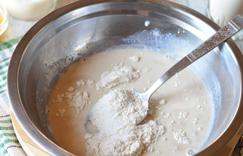 1. Этап. Пышный кулич: Всыпьте в опару пару ложек муки.