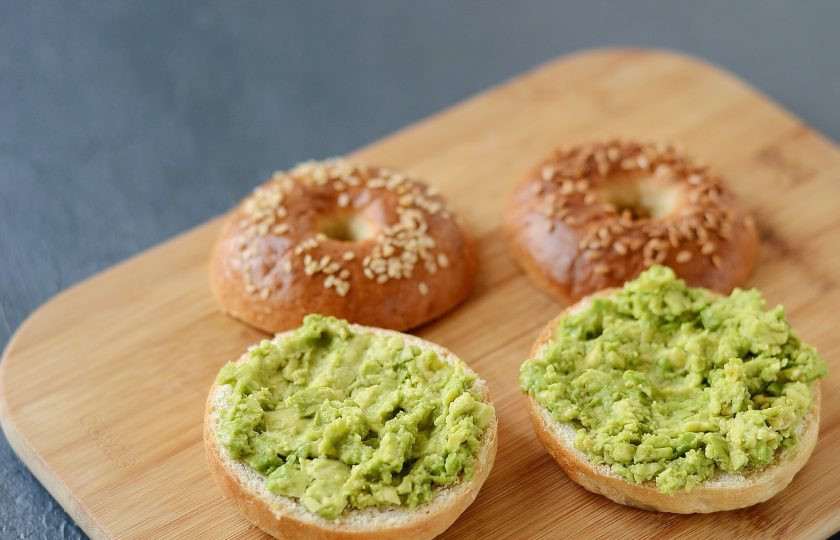 1. Этап. Бейгл с грибами и авокадо: Разрежьте бейглы пополам. На нижнюю часть выложите размятое авокадо.