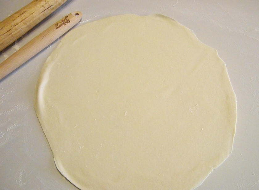 1. Этап. Пельмени с сыром в духовке: Отрежьте небольшой кусочек теста, тонко раскатайте его. Одну сторону листа присыпьте щедро мукой, чтобы она не прилипала к пельменнице.