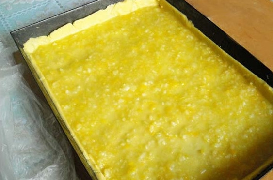 1. Этап. Тертый пирог с лимоном: 6. Положите лимон в горячую воду на 15 минут. Затем нарежьте лимон и освободите его от косточек. Кусочки лимона перекрутите через мясорубку. В перекрученный лимон добавьте сахар. Быстро выложите его на тесто и равномерно распределите по всей поверхности.