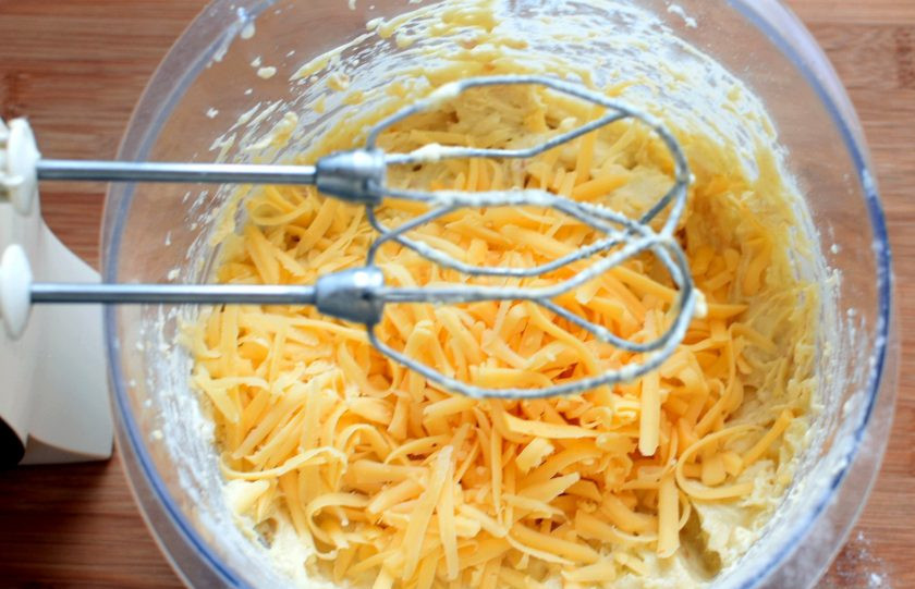 1. Этап. Бургер с острой курицей в вафлях: Всыпьте просеянную с разрыхлителем смесь кукурузной и пшеничной муки, перемешайте до однородности, не слишком усердствуя. Добавьте тертый сыр и вмешайте его в тесто.