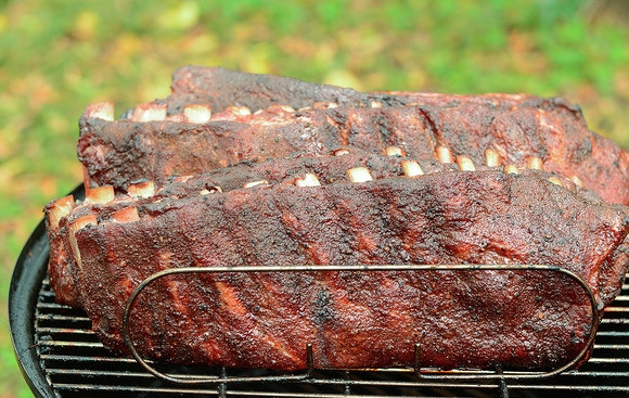 1. Этап. Свиные ребрышки с горчицей: 5. Разогрейте гриль с функцией коптильни (или коптильню) до 170 градусов, как только выгорела древесина и пошел дым, выложите мясо, установите колпак и готовьте 2-3 часа, затем снимите колпак и готовьте еще 2 часа, сбрызгивая мясо соком каждые полчаса.