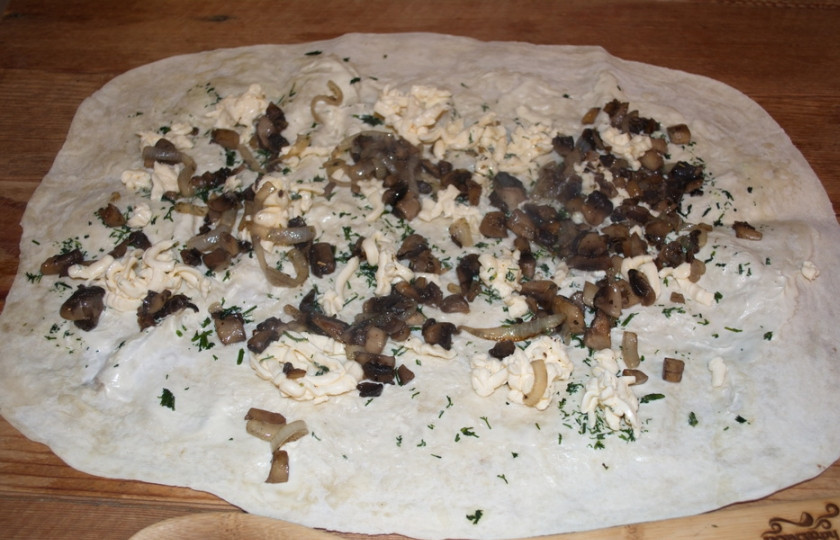 1. Этап. Грибной рулет из лаваша: На терке натрите плавленый сырок. Распределите его по всему лавашу. Измельчите зелень. Обжаренные грибы выложите поверх всего.