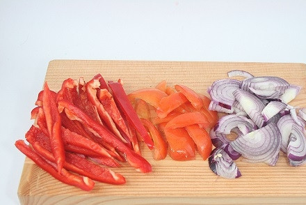 1. Этап. Сырный салат с ветчиной и овощами: Подготовим овощи. Помоем, очистим от шелухи и нарежем тонкими полукольцами лук. У перца удалим сердцевину с семенами, нарежем овощ соломкой. Помидоры нарежем на дольки, можно удалить сердцевинку с семенами.